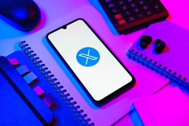 Prag, Çek Cumhuriyeti - 08 18 2025: Merkezinde X logosu sergilenen bir cep telefonu ile ofis malzemeleri düzenlemesi. X, kısa gönderileri ve güncellemeleri paylaşmak için bir platformdur.