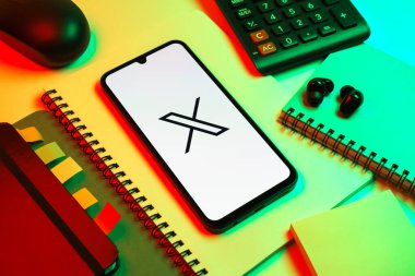 Prag, Çek Cumhuriyeti - 08 18 2025: Merkezinde X logosu sergilenen bir cep telefonu ile ofis malzemeleri düzenlemesi. X, kısa gönderileri ve güncellemeleri paylaşmak için bir platformdur.