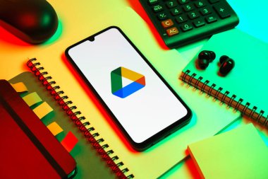 Prag, Çek Cumhuriyeti - 08 18 2025: Merkezde Google Drive logosunu gösteren bir cep telefonu ile ofis malzemeleri düzenlemesi. Google Drive dosyaları çevrimiçi depolamak ve paylaşmak için bir platformdur.