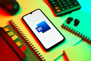 Prag, Çek Cumhuriyeti - 08 18 2025: Merkezinde Word logosu sergilenen bir cep telefonu ile ofis malzemeleri düzenlemesi. Word belge yaratmak ve düzenlemek için bir yazılımdır..