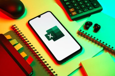 Prag, Çek Cumhuriyeti - 08 18 2025: Excel logosu sergilenen bir cep telefonu ile ofis malzemeleri düzenlemesi. Excel, tablo, veri analizi ve hesaplamalar için bir yazılımdır..