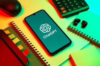 Prag, Çek Cumhuriyeti - 08 18 2025: Merkezinde ChatGPT logosu bulunan bir cep telefonu ile ofis malzemeleri düzenlemesi. ChatGPT metin üretmek ve soruları cevaplamak için bir yapay zeka sohbet robotudur..