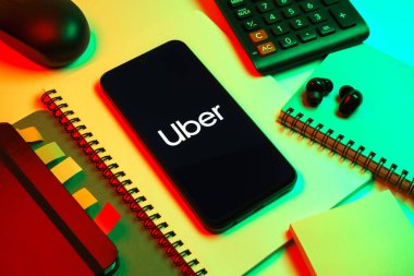 Prag, Çek Cumhuriyeti - 08 18 2025: Merkezde Uber logosu gösteren bir cep telefonu ile ofis malzemeleri düzenlemesi. Uber ulaşım ve dağıtım hizmetleri için bir gezinti selamlama uygulaması.