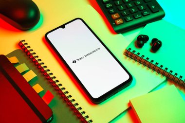Prag, Çek Cumhuriyeti - 08 18 2025: Merkezinde Texas Instruments logosu bulunan bir cep telefonu ile ofis malzemeleri düzenlemesi. Texas Instruments yarı iletken ve elektronik üreten bir şirket..