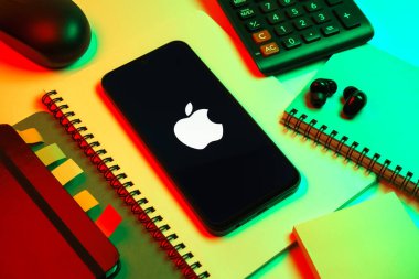 Prag, Çek Cumhuriyeti - 08 18 2025: Merkezi Apple logosunu gösteren bir cep telefonu ile ofis malzemeleri düzenlemesi. Apple iPhone, bilgisayar ve hizmet üreten bir teknoloji şirketidir..