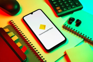 Prag, Çek Cumhuriyeti - 08 18 2025: Merkezinde Commonwealth Bank logosu bulunan bir cep telefonu ile ofis malzemeleri düzenlemesi. Commonwealth Bank, Avustralya 'da finansal hizmetler sağlayan bir bankadır..