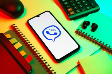Prag, Çek Cumhuriyeti - 08 18 2025: Merkezde Viber logosunu gösteren bir cep telefonu ile ofis malzemeleri düzenlemesi. Viber aramalar, mesajlar ve medya paylaşımı için bir mesajlaşma uygulamasıdır.
