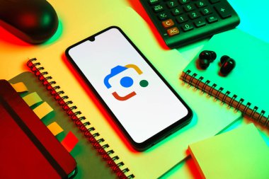 Prag, Çek Cumhuriyeti - 08 18 2025: Merkezde Google Lens logosunu gösteren bir cep telefonu ile ofis malzemeleri düzenlemesi. Google Lens, resimlerdeki görsel arama ve bilgi için kullanılan bir araçtır..