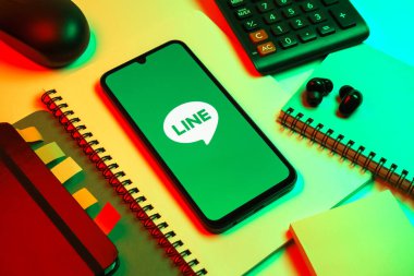 Prag, Çek Cumhuriyeti - 08 18 2025: Merkezinde hat logosu sergilenen bir cep telefonu ile ofis malzemeleri düzenlemesi. Line aramalar, mesajlar ve çokluortam paylaşımı için bir mesajlaşma uygulamasıdır.