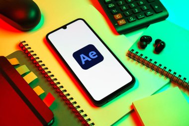 Prag, Çek Cumhuriyeti - 08 18 2025: Ofis malzemelerinin merkezde After Effects logosu sergilenen bir cep telefonu ile düzenlenmesi. After Effects hareket grafikleri ve görsel efektler için bir yazılımdır..