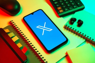 Prag, Çek Cumhuriyeti - 08 18 2025: Merkezinde X logosu sergilenen bir cep telefonu ile ofis malzemeleri düzenlemesi. X, kısa gönderileri ve güncellemeleri paylaşmak için bir platformdur.