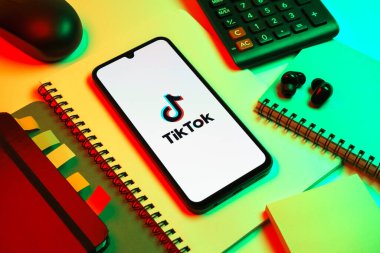 Prag, Çek Cumhuriyeti - 08 18 2025: Merkezde TikTok logosunu gösteren bir cep telefonu ile ofis malzemeleri düzenlemesi. TikTok kısa, yaratıcı ve viral video platformu.