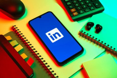 Prag, Çek Cumhuriyeti - 08 18 2025: Merkezde LinkedIn logosunu gösteren bir cep telefonu ile ofis malzemeleri düzenlemesi. LinkedIn, insanları ve şirketleri birbirine bağlayan profesyonel bir ağ..