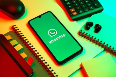 Prag, Çek Cumhuriyeti - 08 18 2025: Ofis malzemelerinin merkezde WhatsApp logosunu gösteren bir cep telefonu ile düzenlenmesi. WhatsApp mesaj, çağrı ve medya göndermek için bir uygulamadır.
