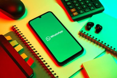Prag, Çek Cumhuriyeti - 08 18 2025: Ofis malzemelerinin merkezde WhatsApp logosunu gösteren bir cep telefonu ile düzenlenmesi. WhatsApp mesaj, çağrı ve medya göndermek için bir uygulamadır.