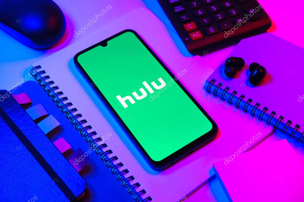 Prague, Czechia - 08 18 2025: An arrangement of office supplies with a mobile phone in the center displaying Hulu logo. Hulu is a streaming platform for TV shows, movies, and live TV.