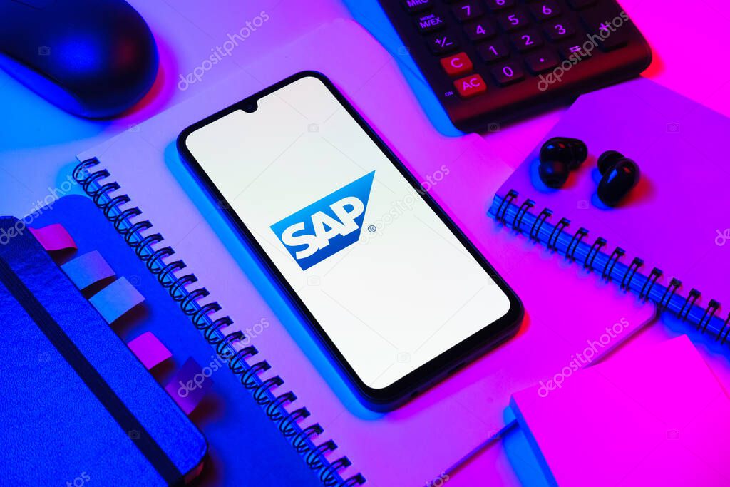 Prague, Czechia - 08 18 2025: An arrangement of office supplies with a mobile phone in the center displaying SAP logo. SAP is a software company providing enterprise applications and solutions.