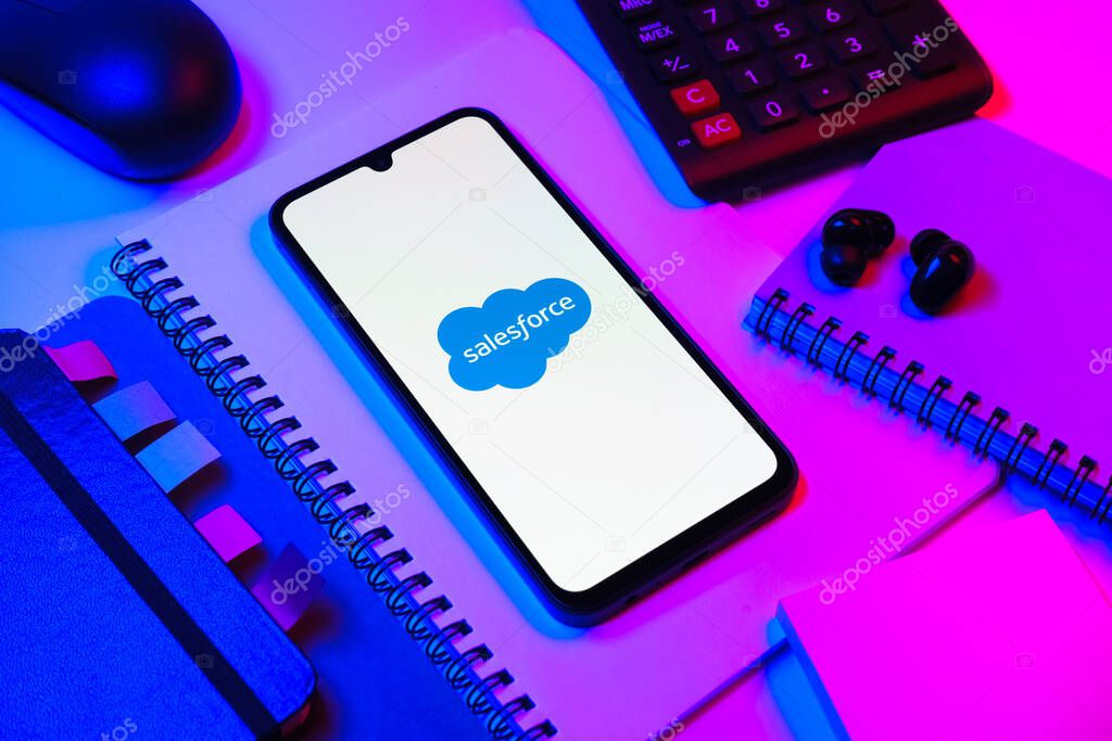 Prague, Czechia - 08 18 2025: An arrangement of office supplies with a mobile phone in the center displaying Salesforce logo. Salesforce is a platform for customer relationship management and cloud services.