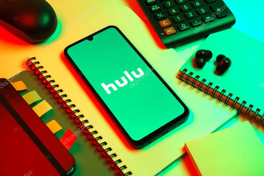 Prague, Czechia - 08 18 2025: An arrangement of office supplies with a mobile phone in the center displaying Hulu logo. Hulu is a streaming platform for TV shows, movies, and live TV.