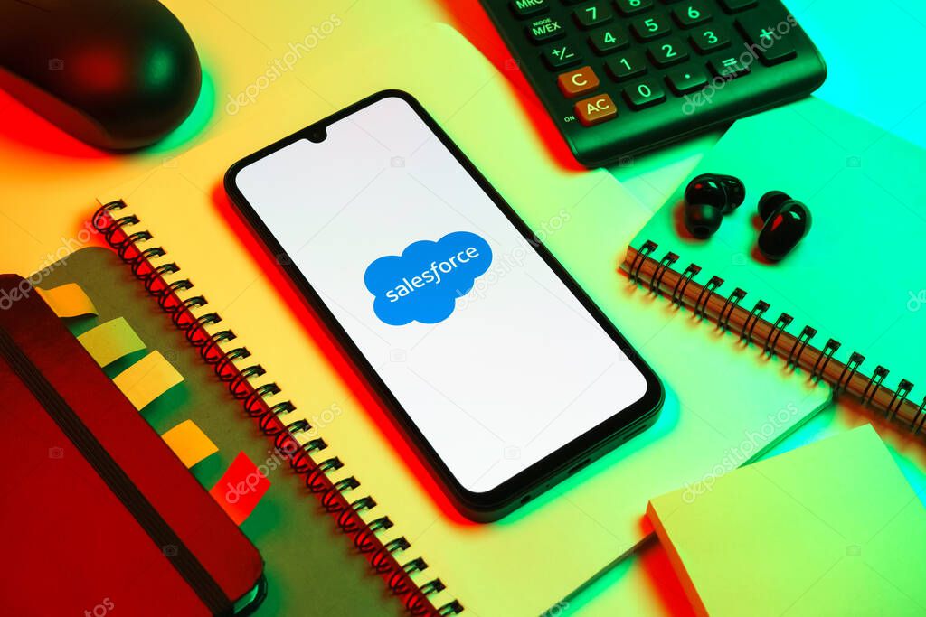 Prague, Czechia - 08 18 2025: An arrangement of office supplies with a mobile phone in the center displaying Salesforce logo. Salesforce is a platform for customer relationship management and cloud services.