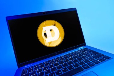 Prag, Çek Cumhuriyeti - 08 12 2025: Dogecoin logosunu gösteren bir dizüstü bilgisayarın dinamik yakın çekimi. Dogecoin, paylaşımcı işlemler için kullanılan bir şifreli para birimidir.