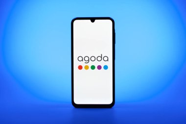 Prag, Çek Cumhuriyeti - 08 10 2025: Arka planda duran bir cep telefonu Agoda logosunu gösteriyor. Agoda, otelleri ve seyahat yerlerini ayırtmak için bir platform..