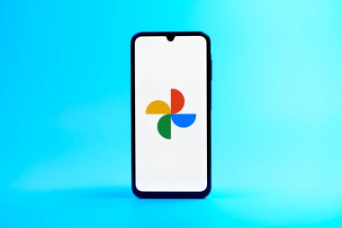Prag, Çek Cumhuriyeti - 08 10 2025: Tek tip arka planda duran bir cep telefonu Google Photos logosunu görüntüler. Google Fotoğrafları fotoğraf ve videoları saklamak ve düzenlemek için bir platformdur.