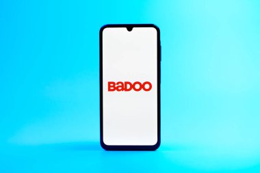 Prag, Çek Cumhuriyeti - 08 10 2025: Üniformalı arka planda duran bir cep telefonu Badoo logosunu gösteriyor. Badoo insanlarla tanışmak ve iletişim kurmak için bir randevu uygulaması..
