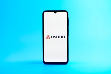 Prag, Çek Cumhuriyeti - 08 10 2025: Arka planda duran bir cep telefonu Asana logosunu gösteriyor. Asana görev yönetimi ve takım işbirliği için bir platformdur..