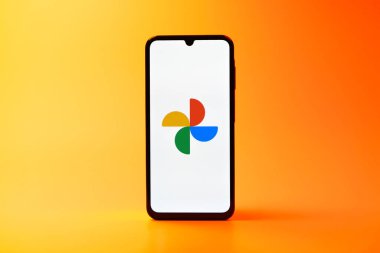 Prag, Çek Cumhuriyeti - 08 10 2025: Tek tip arka planda duran bir cep telefonu Google Photos logosunu görüntüler. Google Fotoğrafları fotoğraf ve videoları saklamak ve düzenlemek için bir platformdur.