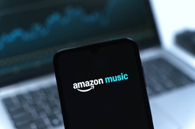 Prag, Çek Cumhuriyeti - 08 12 2025: Dizüstü bilgisayarın önünde duran bir cep telefonu Amazon Müzik logosunu gösteriyor. Amazon Müzik müzik müzik için bir platformdur..