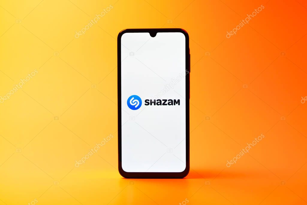 Prague, Czechia - 08 10 2025: A mobile phone standing on a uniform background displays the Shazam logo. Shazam is an app for identifying songs and music tracks.
