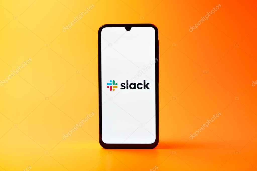 Prague, Czechia - 08 10 2025: A mobile phone standing on a uniform background displays the Slack logo. Slack is a platform for team messaging and workplace communication.