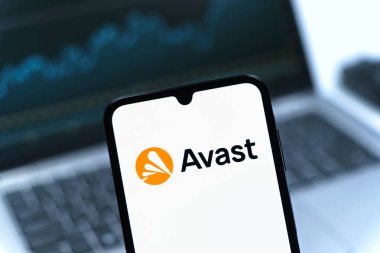 Prag, Çek Cumhuriyeti - 08 12 2025: Bir dizüstü bilgisayarın önünde duran bir cep telefonu Avast logosunu gösteriyor. Avast antivirüs ve siber güvenlik için bir platformdur.