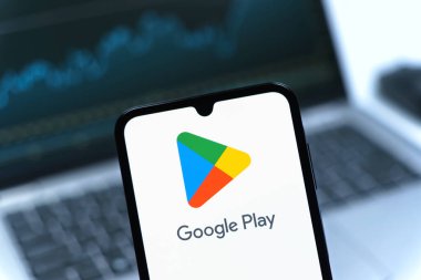 Prag, Çek Cumhuriyeti - 08 12 2025: Bir dizüstü bilgisayarın önünde duran bir cep telefonu Google Play logosunu gösteriyor. Google Play uygulamaları, oyunları ve dijital içeriği indirmek için bir platformdur.