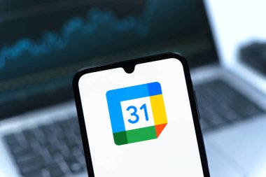 Prag, Çek Cumhuriyeti - 08 12 2025: Bir dizüstü bilgisayarın önünde duran bir cep telefonu Google takvim logosunu görüntüler. Google Takvimi olayları zamanlamak ve yönetmek için bir platformdur.