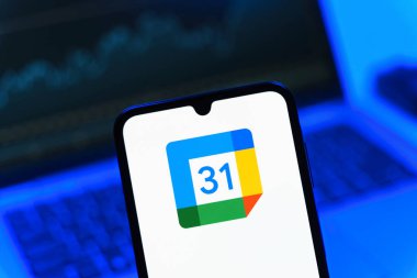 Prag, Çek Cumhuriyeti - 08 12 2025: Bir dizüstü bilgisayarın önünde duran bir cep telefonu Google takvim logosunu görüntüler. Google Takvimi olayları zamanlamak ve yönetmek için bir platformdur.