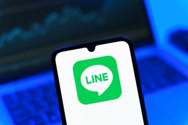 Prag, Çek Cumhuriyeti - 08 12 2025: Dizüstü bilgisayarın önünde duran bir cep telefonu Line logosunu gösteriyor. Line aramalar, mesajlar ve çokluortam paylaşımı için bir mesajlaşma uygulamasıdır.