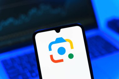 Prag, Çek Cumhuriyeti - 08 12 2025: Bir dizüstü bilgisayarın önünde duran bir cep telefonu Google Lens logosunu gösteriyor. Google Lens, resimlerdeki görsel arama ve bilgi için kullanılan bir araçtır..