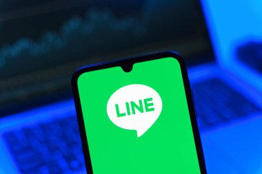 Prag, Çek Cumhuriyeti - 08 12 2025: Dizüstü bilgisayarın önünde duran bir cep telefonu Line logosunu gösteriyor. Line aramalar, mesajlar ve çokluortam paylaşımı için bir mesajlaşma uygulamasıdır.