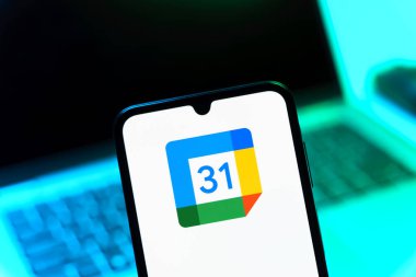 Prag, Çek Cumhuriyeti - 08 12 2025: Bir dizüstü bilgisayarın önünde duran bir cep telefonu Google takvim logosunu görüntüler. Google Takvimi olayları zamanlamak ve yönetmek için bir platformdur.