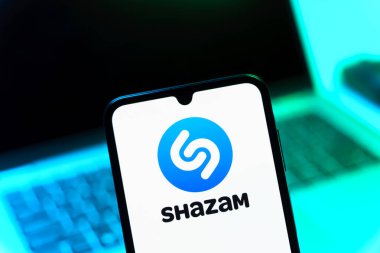 Prag, Çek Cumhuriyeti - 08 12 2025: Dizüstü bilgisayarın önünde duran bir cep telefonu Shazam logosunu gösteriyor. Shazam şarkıları ve müzik parçalarını tanımlamak için bir uygulamadır.