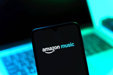 Prag, Çek Cumhuriyeti - 08 12 2025: Dizüstü bilgisayarın önünde duran bir cep telefonu Amazon Müzik logosunu gösteriyor. Amazon Müzik müzik müzik için bir platformdur..