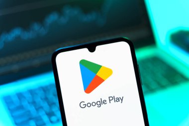 Prag, Çek Cumhuriyeti - 08 12 2025: Bir dizüstü bilgisayarın önünde duran bir cep telefonu Google Play logosunu gösteriyor. Google Play uygulamaları, oyunları ve dijital içeriği indirmek için bir platformdur.