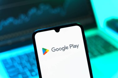 Prag, Çek Cumhuriyeti - 08 12 2025: Bir dizüstü bilgisayarın önünde duran bir cep telefonu Google Play logosunu gösteriyor. Google Play uygulamaları, oyunları ve dijital içeriği indirmek için bir platformdur.