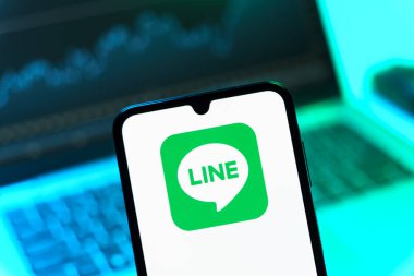 Prag, Çek Cumhuriyeti - 08 12 2025: Dizüstü bilgisayarın önünde duran bir cep telefonu Line logosunu gösteriyor. Line aramalar, mesajlar ve çokluortam paylaşımı için bir mesajlaşma uygulamasıdır.