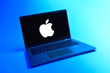 Prague, Czechia - 08 12 2025: A dynamic view of a laptop on a uniform background displaying the Apple logo. Apple is a technology company making iPhones, computers, and services.