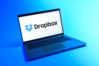 Prague, Czechia - 08 12 2025: A dynamic view of a laptop on a uniform background displaying the Dropbox logo. Dropbox is a platform for cloud storage and file sharing.