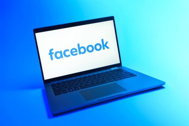 Prague, Czechia - 08 12 2025: A dynamic view of a laptop on a uniform background displaying the Facebook logo. Facebook is a social media platform for connecting and sharing content.