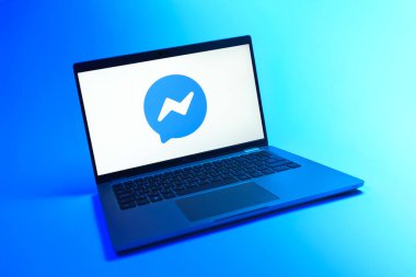 Prague, Czechia - 08 12 2025: A dynamic view of a laptop on a uniform background displaying the Messenger logo. Messenger is a platform for messaging and chatting on Facebook.